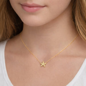 gold starfish necklace on model